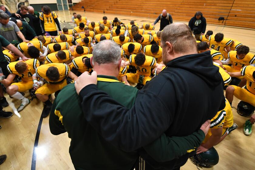 PARADISE, CALIFORNIA NOVEMBER 15, 2019-Paradise High School head coach Rick Prinz and assistant coach Andy Hopper lead a prayer before a playoff game against Live Oak. (Wally Skalij/Los Angerles Times)