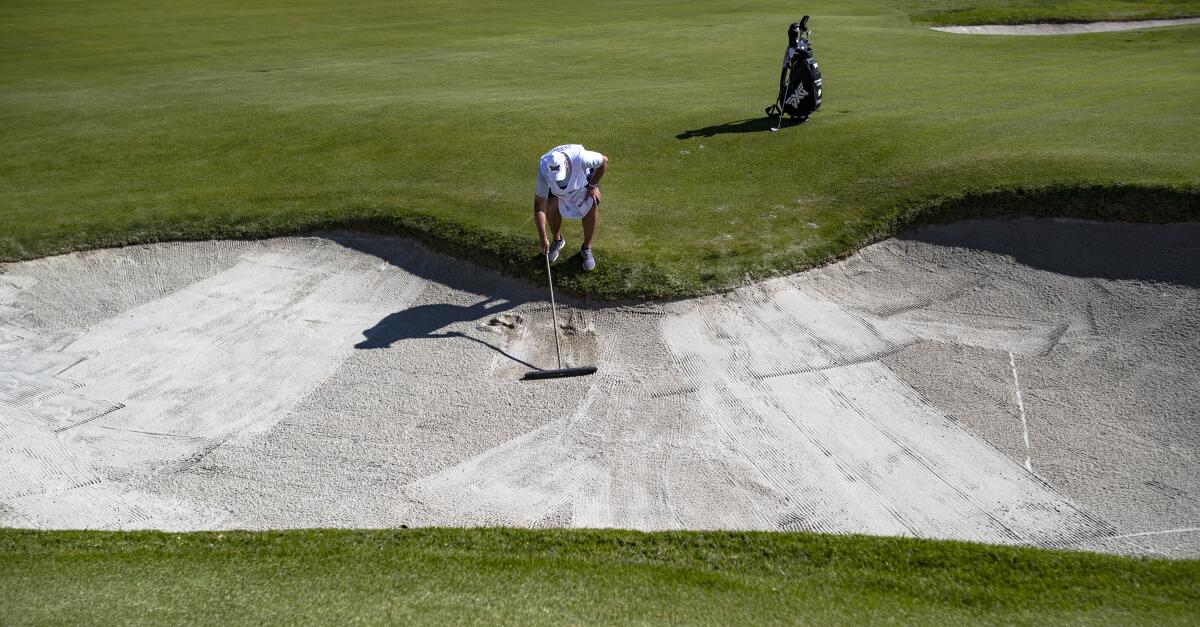 John Ellis, caddie for Wyndham Clark, rakes the sand trap on the second hole at Riviera Country Club during the second round of the Genesis Invitational on Friday.