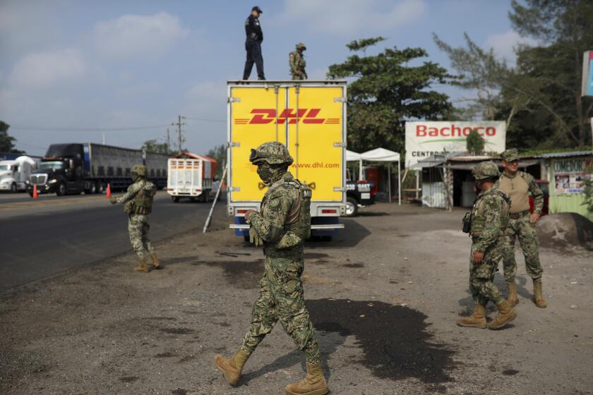 In this Nov. 26, 2019 photo, soldiers guard a truck that was moving dozens of Central American migrants, at an immigration checkpoint where the truck was stopped in Medellín de Bravo, Veracruz state, Mexico. The Mexican government has denounced smuggling networks that use semi-trailers, often painted with the logos of legitimate companies to disguise their cargo, and where there's a risk the migrants could suffocate. (AP Photo/Felix Marquez)
