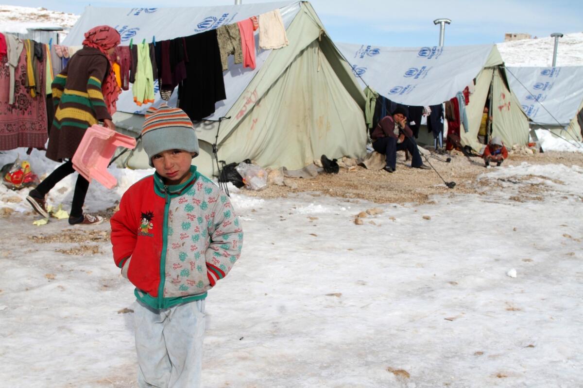 A Syrian child stands in a snowy refugee camp in the Lebanese border town of Arsal.
