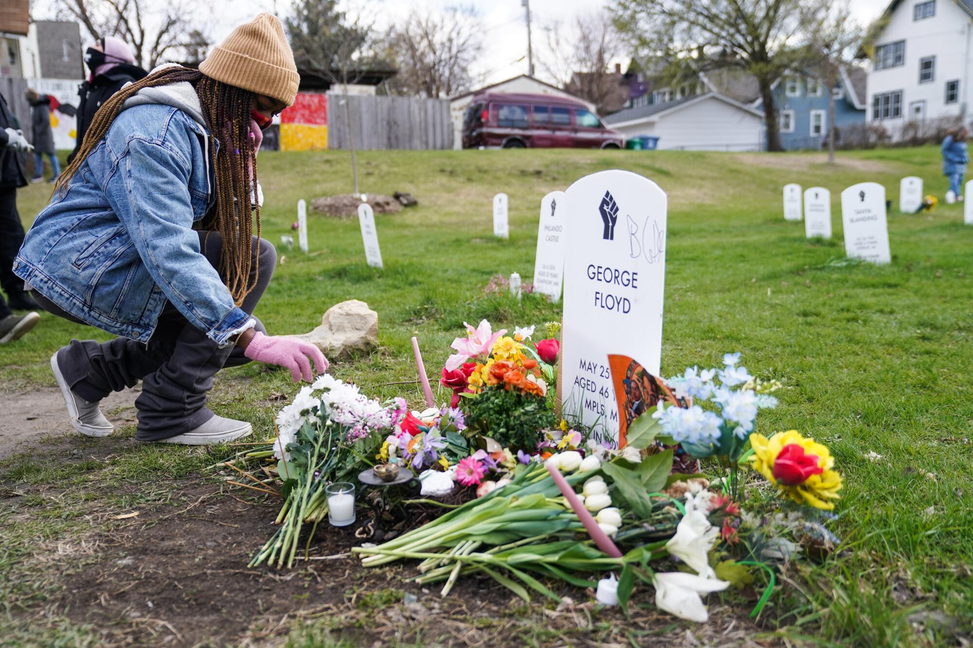 A woman lays flowers at a memorial