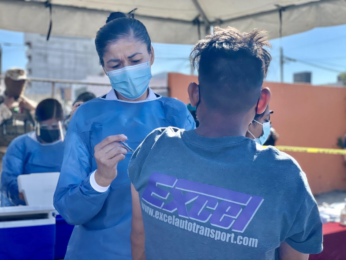 A nurse vaccinates Hector Cruz, 24, originally from Honduras, at the El Chaparral camp in Tijuana on Tuesday.