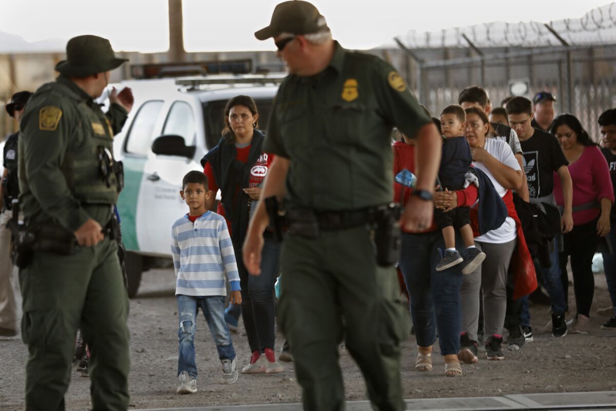 Migrants are led to a holding area in El Paso. In Washington, the House approved a bill to provide funding to address the humanitarian crisis after changes were made to strengthen protections for migrant children.