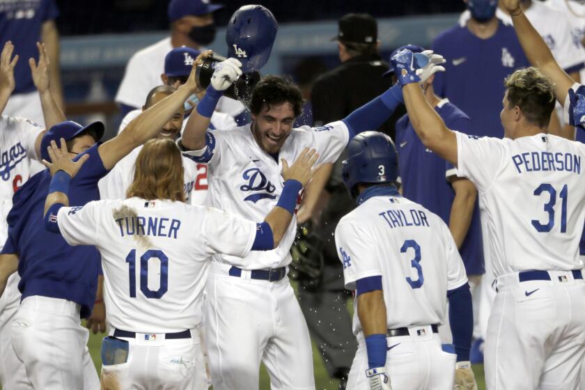 Los Angeles Dodgers' Cody Bellinger, center, is welcomed by teammates after his game-ending solo home run during the ninth inning of a baseball game against the Colorado Rockies in Los Angeles, Saturday, Aug. 22, 2020. (AP Photo/Alex Gallardo)