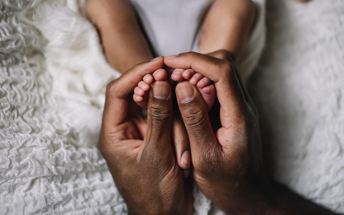 Adult hands hold a baby's feet 