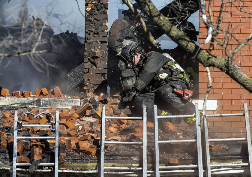 FILE - A firefighter reacts after a pile of bricks falls on him from a window eve as crews work to extinguish the fire in the structure in St. Louis, Mo., Thursday, Jan. 13, 2022. Leaders in St. Louis and Baltimore are considering changes in dealing with fires at vacant homes after firefighters in both cities died at abandoned structures in January. (Colter Peterson/St. Louis Post-Dispatch via AP, File)
