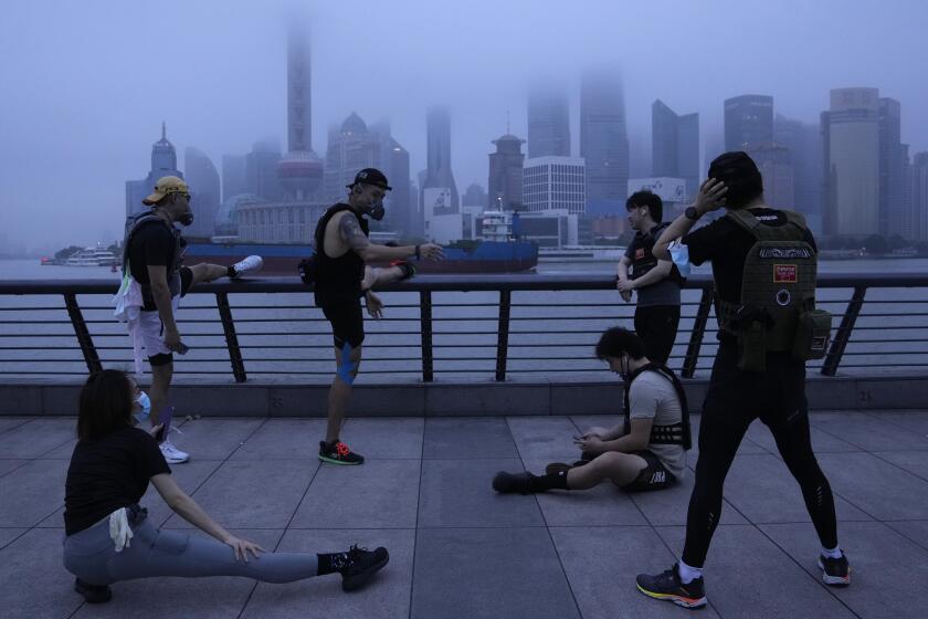 Vecinos con mascarillas hacen ejercicio en el paseo marítimo al amanecer del miércoles 1 de junio de 2022 en Shanghái. (AP Foto/Ng Han Guan)