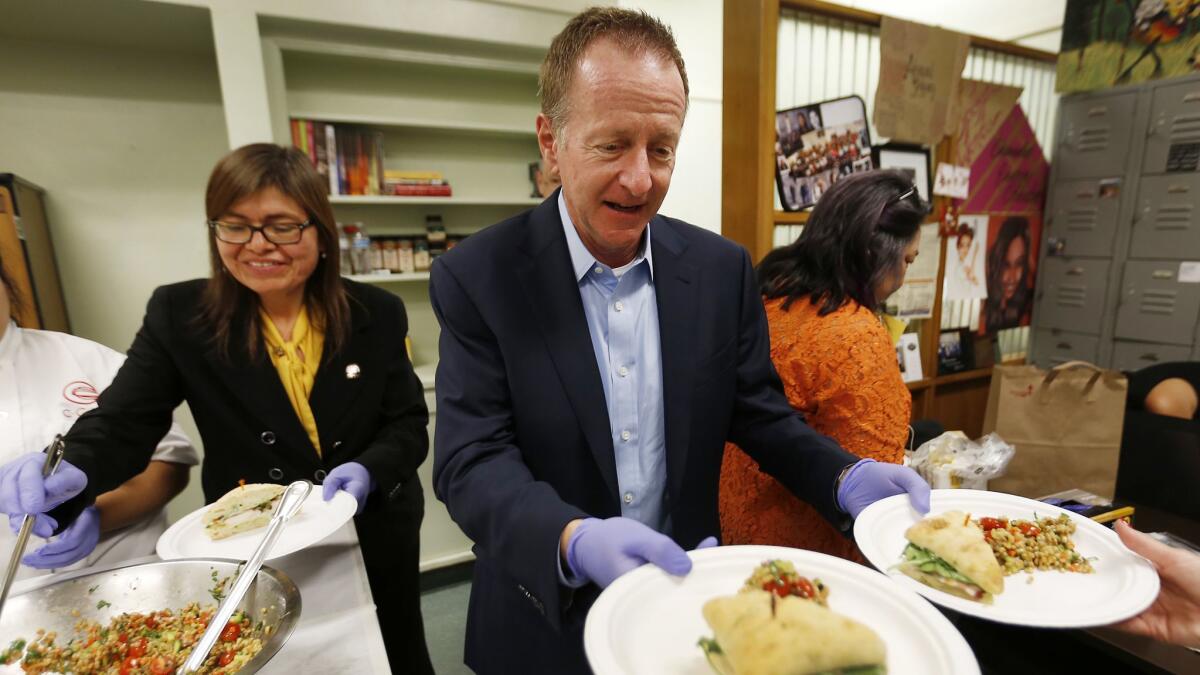 L.A. Unified Supt. Austin Beutner serves up dishes prepared by culinary students and graduates from San Fernando High School with Principal Flora Mendoza-Warner. He'd like to serve up more such learning opportunities for students.