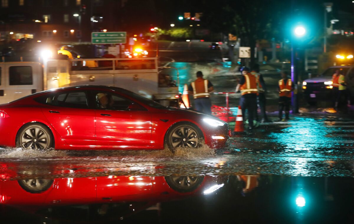 A car drives down a flooded Tenth Ave. after a water main broke at A Street and Eleventh Ave., Nov. 21, 2021 in San Diego.