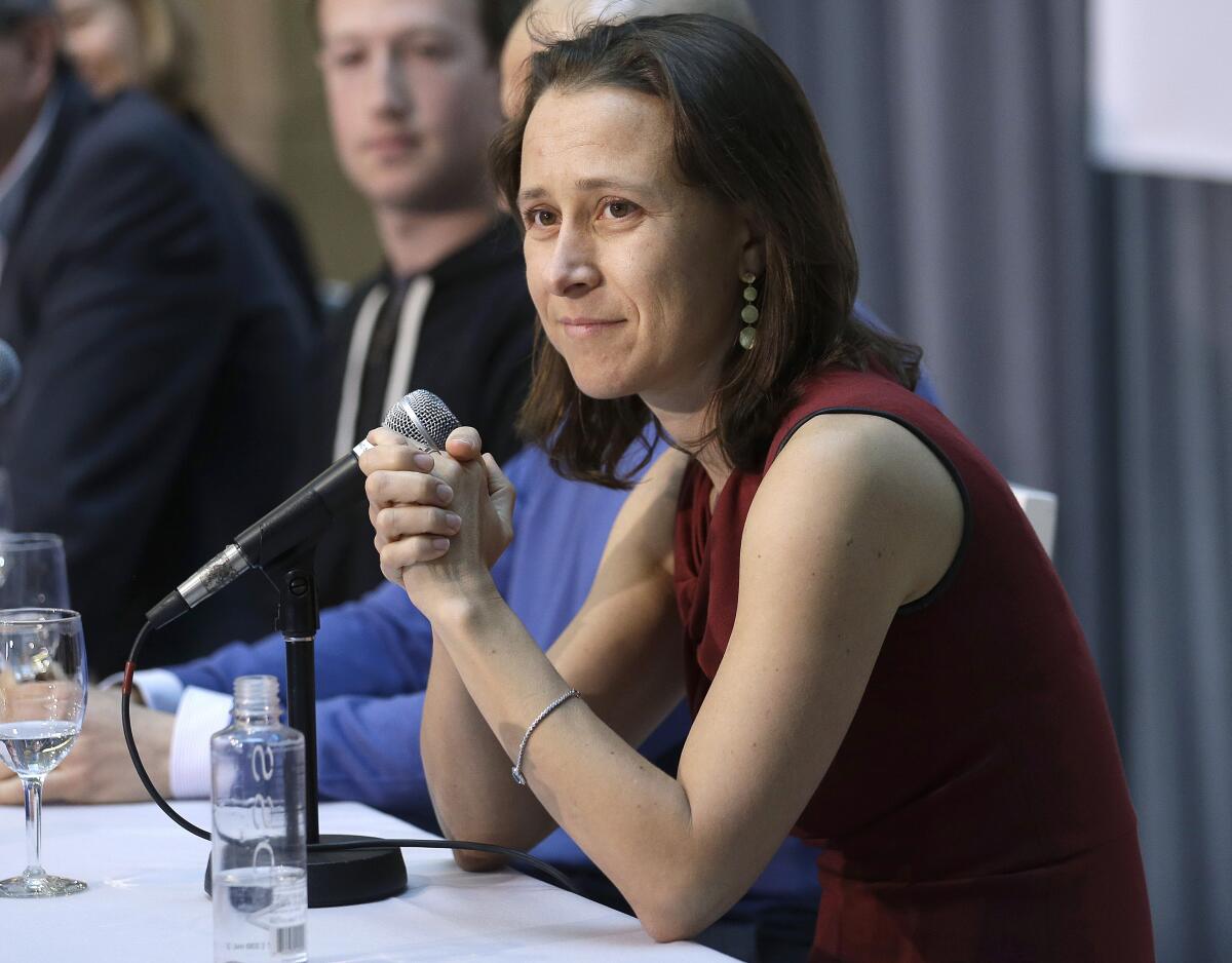 Anne Wojcicki sits in front of a microphone at a table with other people