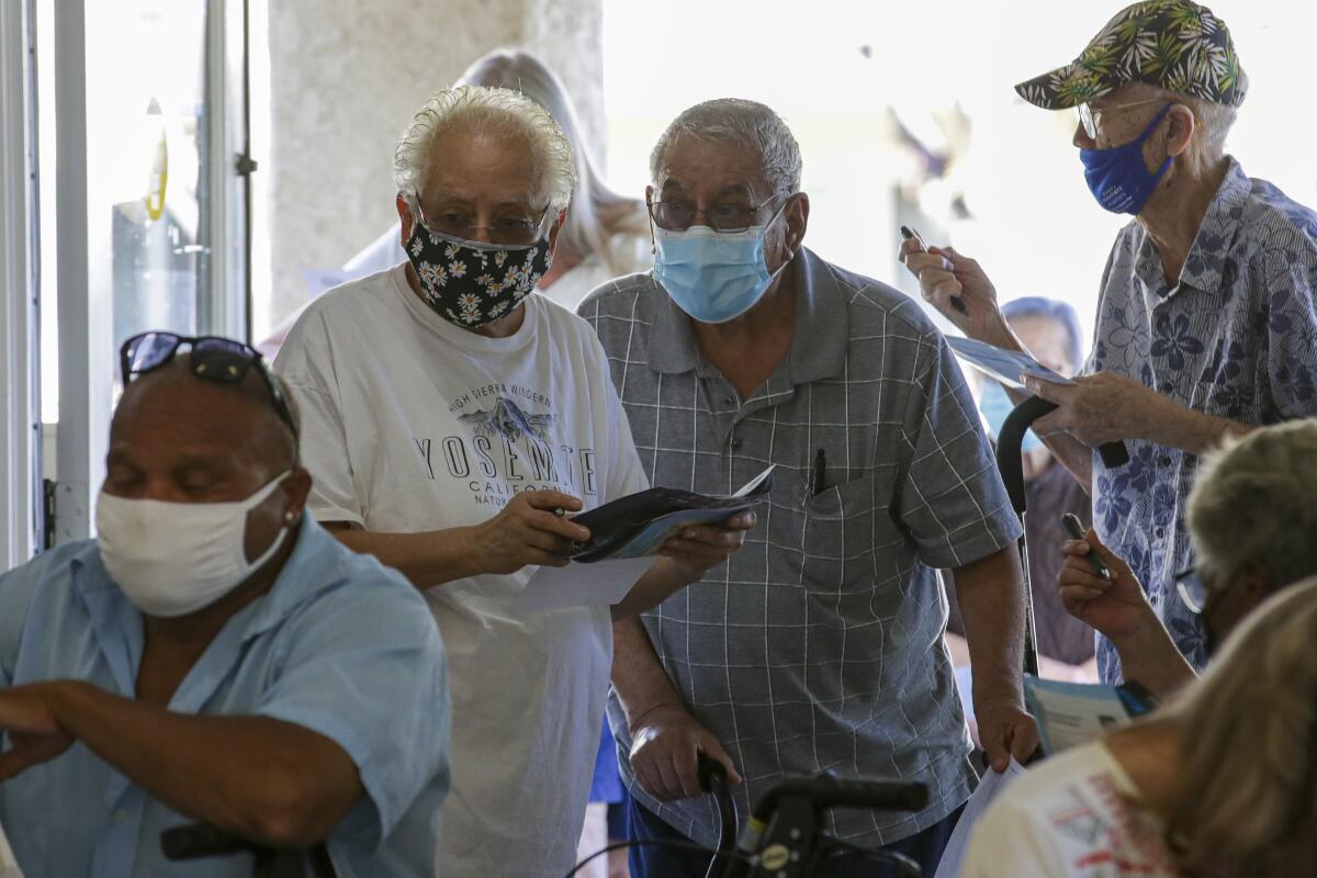 Older men in face masks stand in a line.