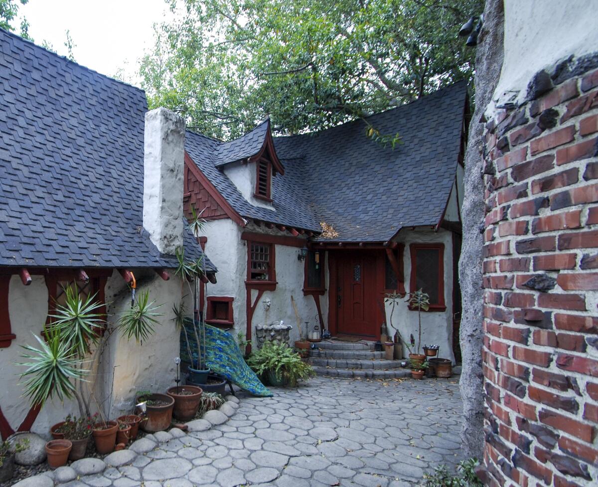 The entrance to a small house with a steeply pitched roof and stone driveway.