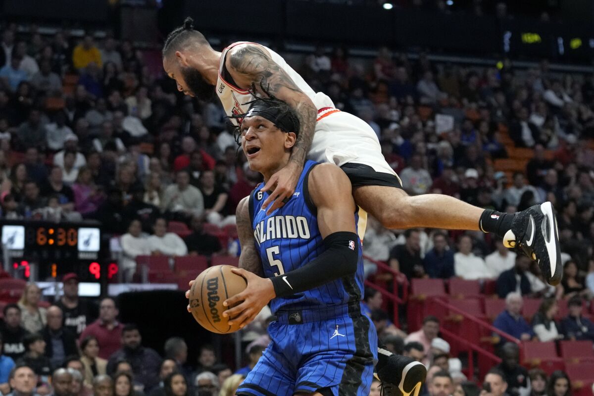 Orlando Magic forward Paolo Banchero (5) is fouled by Miami Heat forward Caleb Martin during the first half of an NBA basketball game, Friday, Jan. 27, 2023, in Miami. (AP Photo/Lynne Sladky)