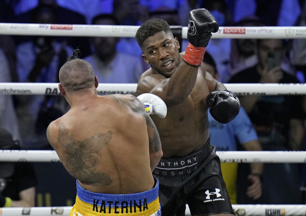 Britain's Anthony Joshua, right, launches a blow at Ukraine's Oleksandr Usyk during their world heavyweight title fight at King Abdullah Sports City in Jeddah, Saudi Arabia, Sunday, Aug. 21, 2022. (AP Photo/Hassan Ammar)