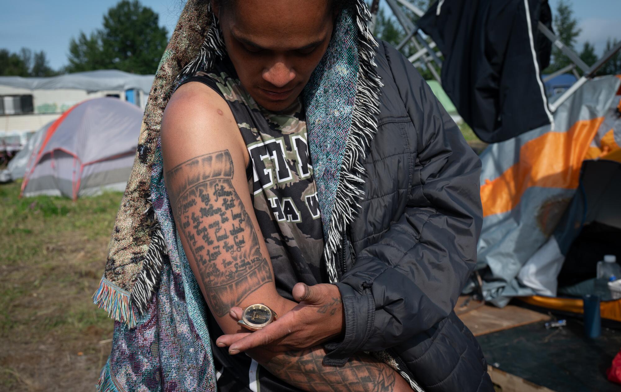 A woman shows a tattoo on her arm.