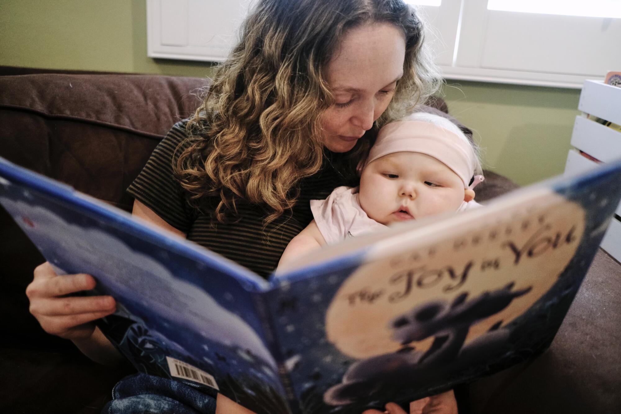 A mother and baby read a book.