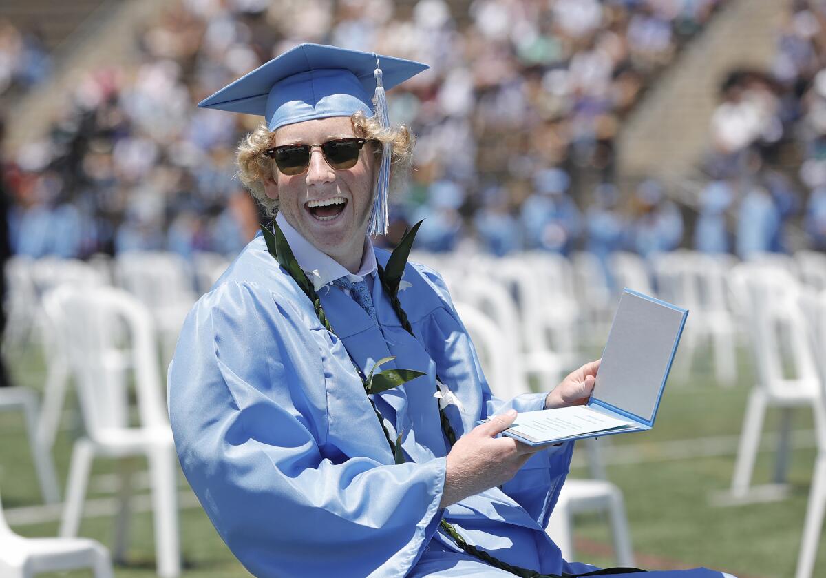 A Corona del Mar graduate is big smiles as he looks over his diploma.