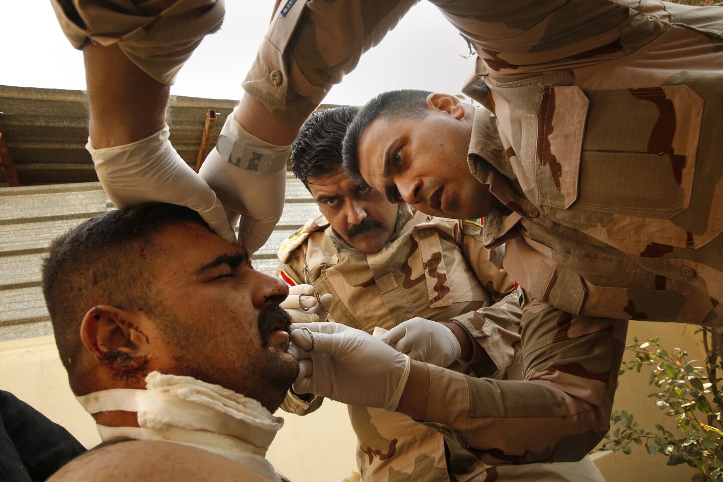 Capt. Osama Fuad Rauf, 33, center, and Maj. Mohammed Hassan Abdullah, left, 35, treat a soldier who was wounded in the fight against Islamic State near Mosul.