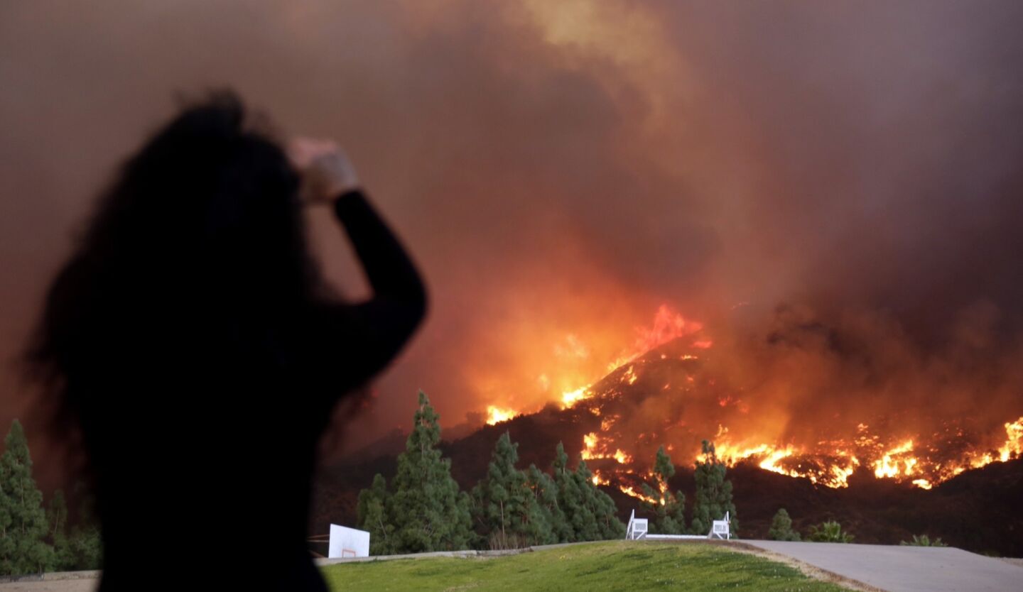 A woman looks at a brush fire that was reported at about 6 a.m. north of Glendora, a foothill community about 30 miles northeast of downtown Los Angeles.
