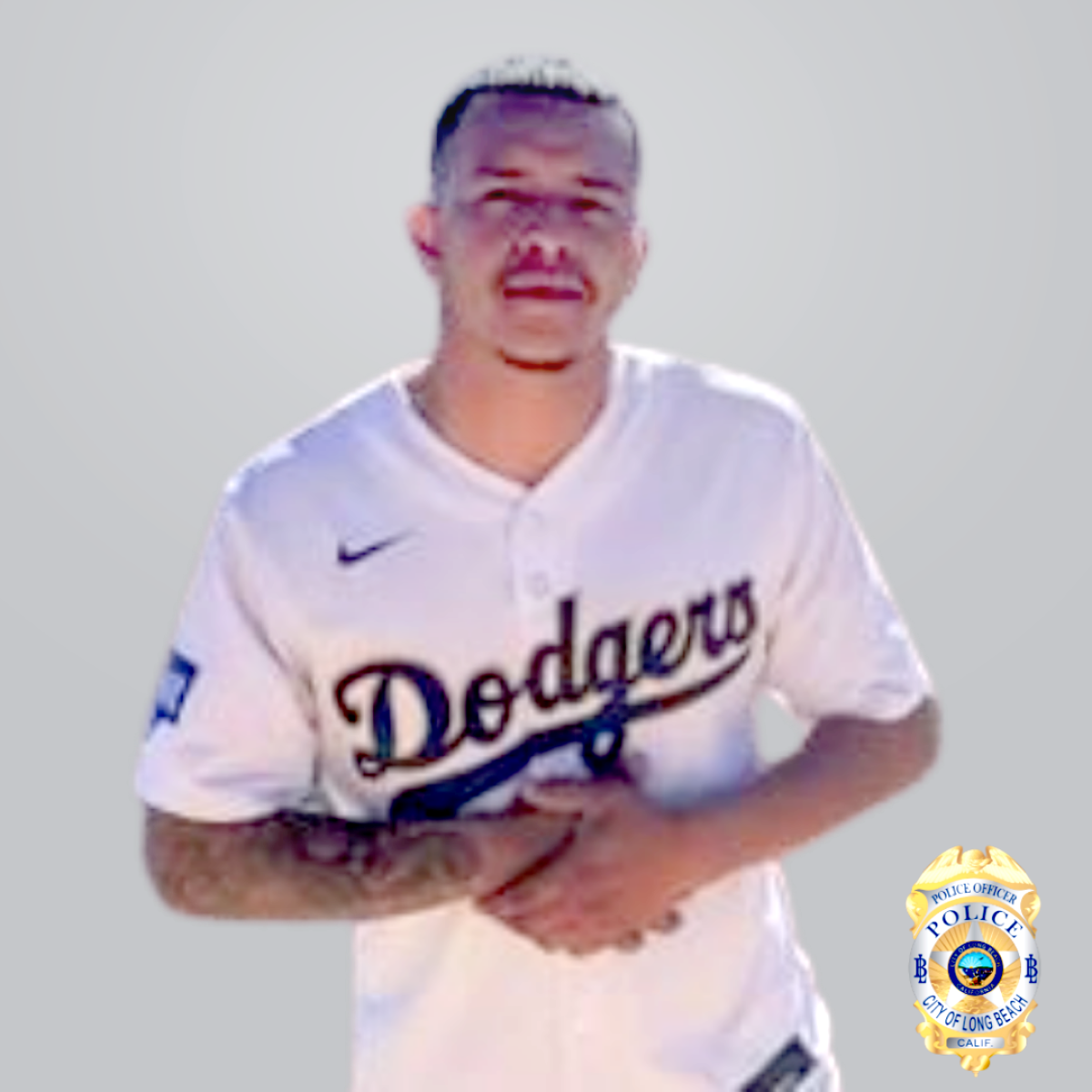 A man wearing a Dodgers jersey with his hands folded across his torso