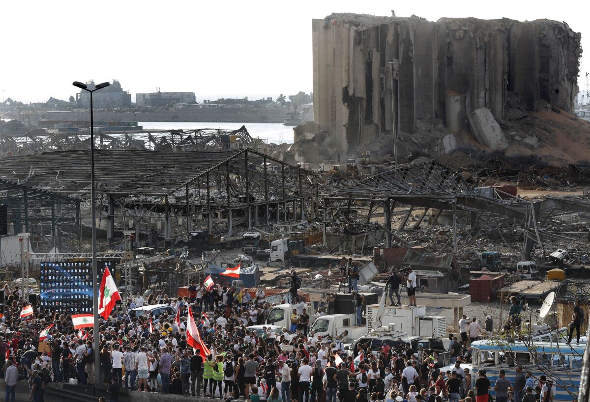 People gather in honor of the victims at the scene of the last week's explosion that killed many and devastated the city, in Beirut, Lebanon, Tuesday, Aug. 11, 2020. (AP Photo/Hussein Malla)