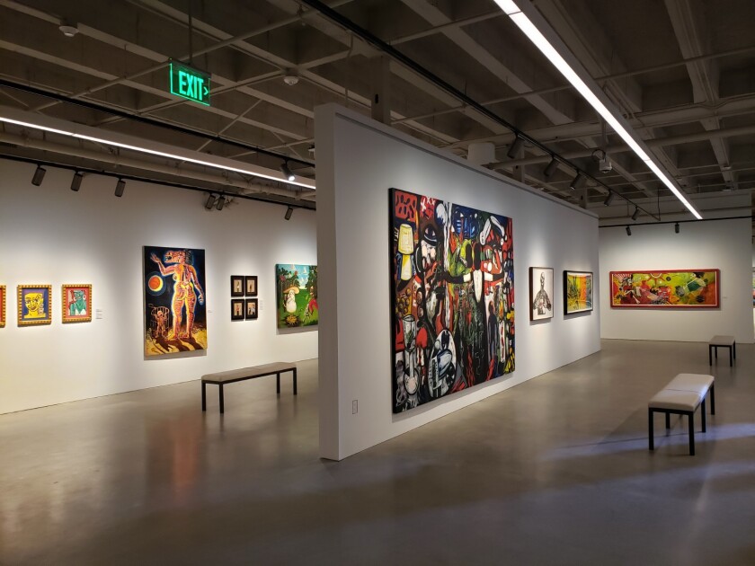 The paintings hang on the white walls of the museum.