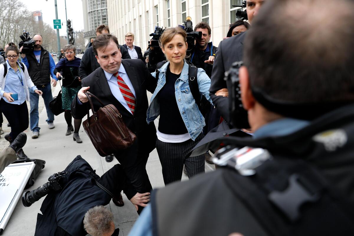 Varios fotógrafos se caen al suelo cuando la actriz Allison Mack abandona el Tribunal Federal hoy, en Brooklyn
