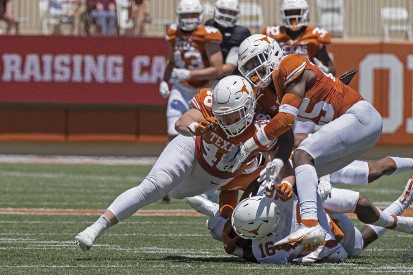 Texas defenders Jake Ehlinger, left, and B.J. Foster, right, tackle Kayvontay Dixon (16) during the first half of the Texas Orange and White Spring Scrimmage football game in Austin, Texas, Saturday, April 24, 2021. (AP Photo/Michael Thomas)