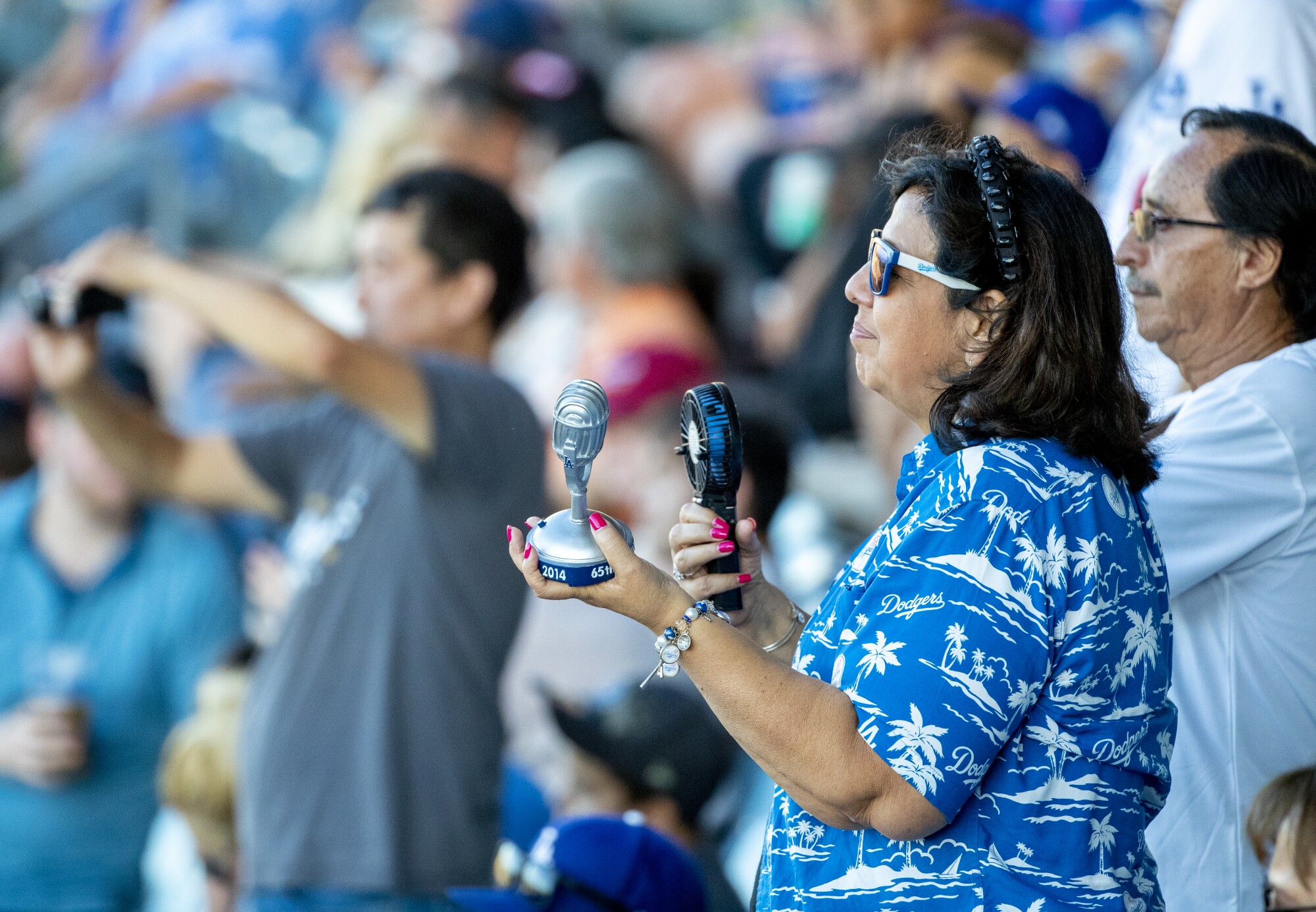 Angie Varella holds a replica microphone during Friday's memorial service for Vin Scully.