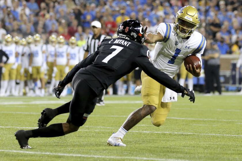 UCLA quarterback Dorian Thompson-Robinson (1) pushes off from Cincinnati cornerback Coby Bryant (7) during the second half of an NCAA college football game Thursday, Aug. 29, 2019, in Cincinnati. (Kareem Elgazzar/The Cincinnati Enquirer via AP)