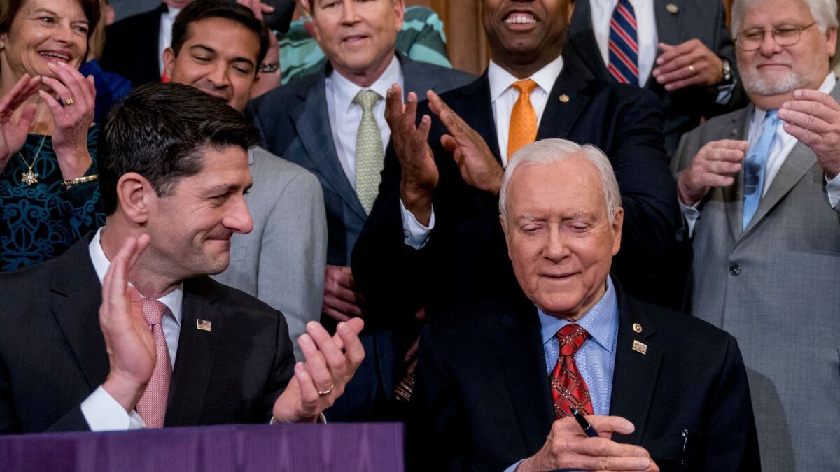 House Speaker Paul Ryan (R-Wis.), left, applauds as Senate Finance Committee Chairman Orrin Hatch (R-Utah) signs the final version of the GOP tax bill at the Capitol on Dec. 21. What's in the bill for you?