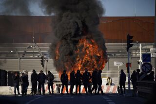 Trabajadores portuarios de pie ante una barricada en llamas junto al puerto de Marsella, en el sur de Francia, el miércoles 22 de marzo de 2023. (AP Foto/Daniel Cole)