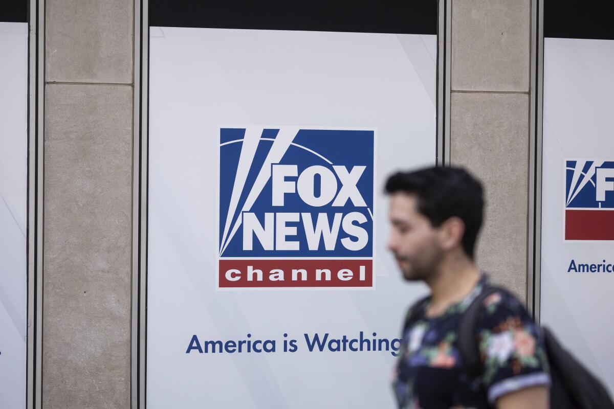 A person walks past a Fox News logo.