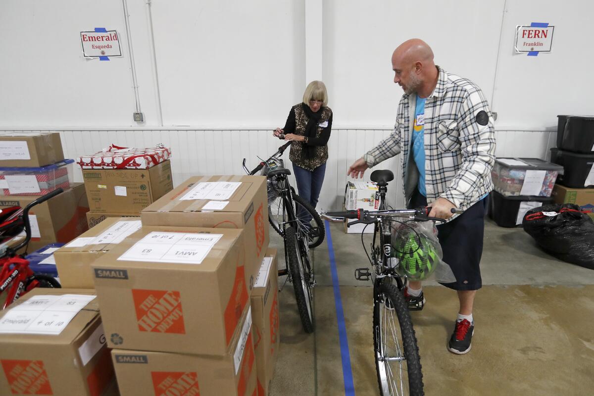 Volunteers Amy Hunt of Newport Beach and Eric Weiner of Huntington Beach organize donations for Share Our Selves' Adopt A Family program Wednesday at the OC Fair & Event Center in Costa Mesa.