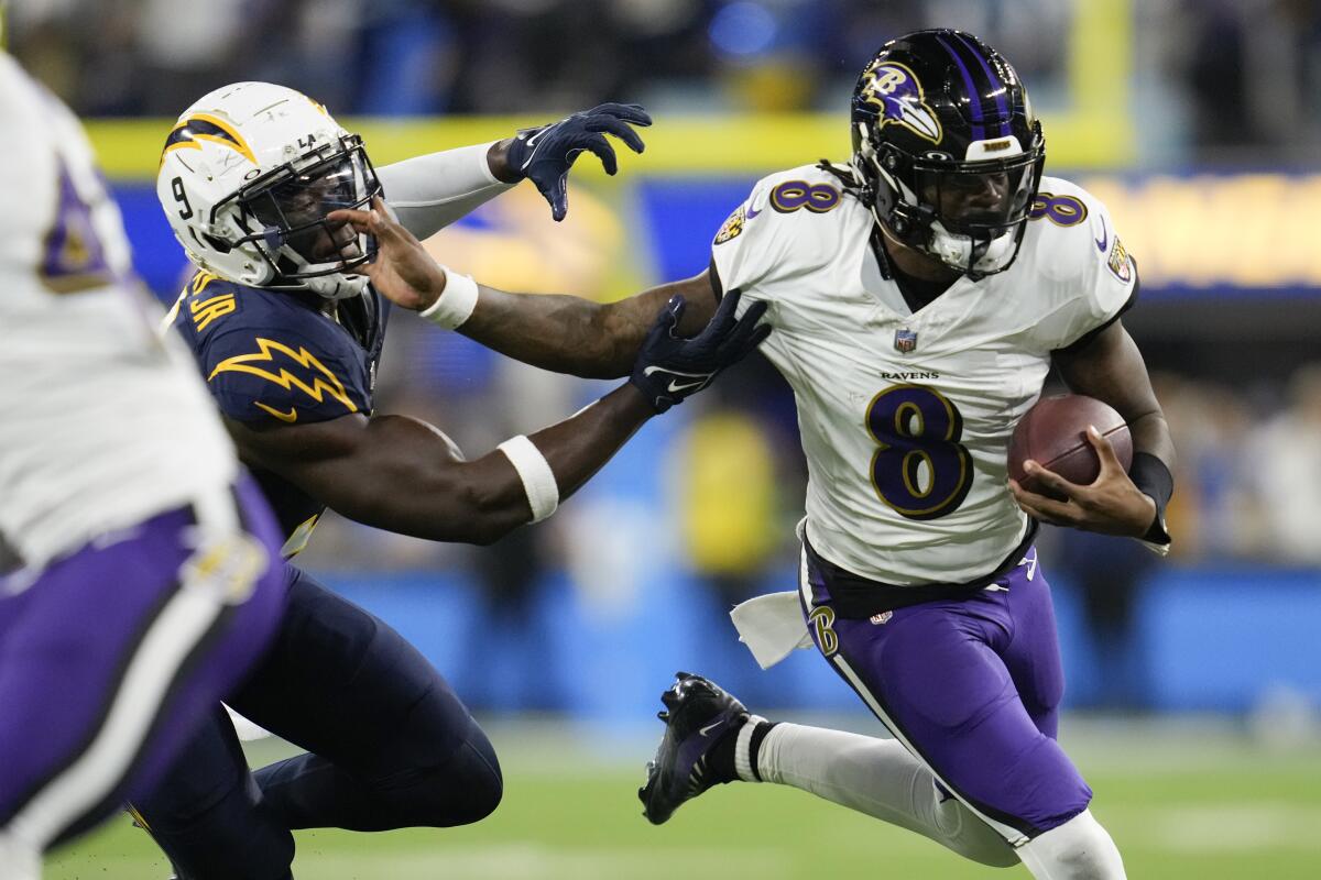 Baltimore quarterback Lamar Jackson fends off Chargers linebacker Kenneth Murray Jr. during a Ravens win on Nov. 27.