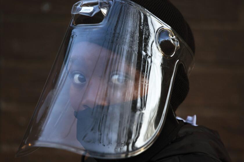FILE — In this Aug. 24, 2020 file photo, a student, wearing a face mask and shield, returns to the Melpark Primary School in Johannesburg after several months of lockdown. Ordinarily, South Africa sees widespread influenza during the winter months, but this year almost none have been found — something unprecedented. School closures, limited public gatherings and calls to wear masks and wash hands have “knocked down the flu,” said Dr. Cheryl Cohen, head of the institute's respiratory program. (AP Photo/Denis Farrell, File)