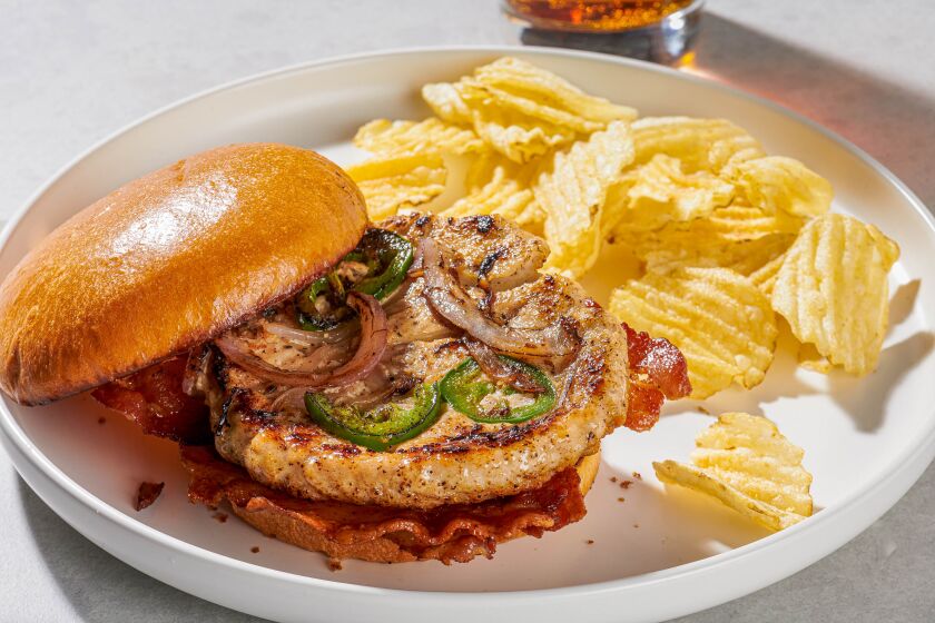 A chicken burger served on a plate with potato chips.