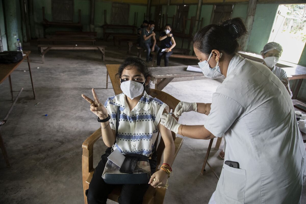 An Indian woman getting vaccinated with a dose of COVAXIN against the coronavirus gestures to camera in Gauhati, Assam, India, Monday, May 10, 2021. (AP Photo/Anupam Nath)