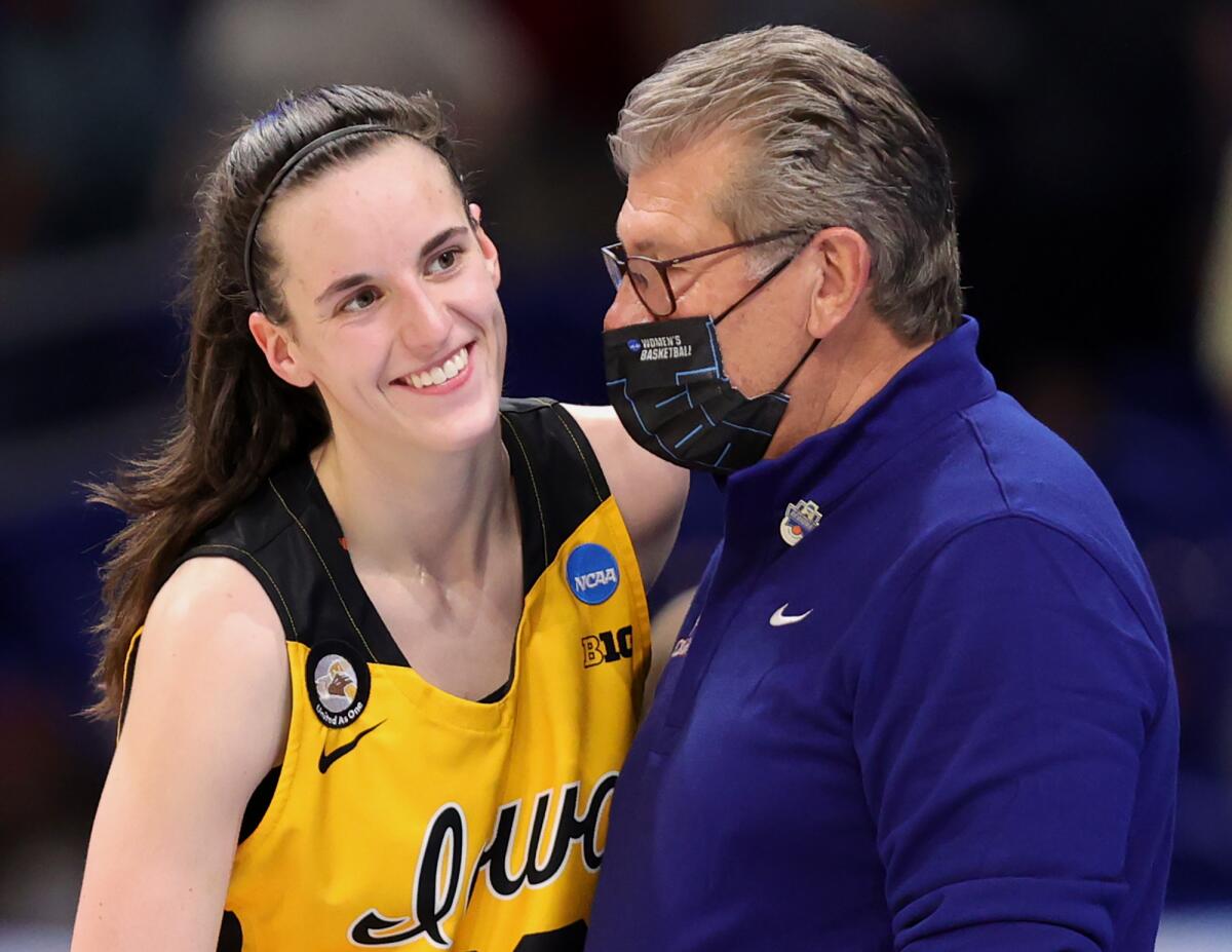 UConn coach Geno Auriemma wears a mask while speaking with Iowa's Caitlin Clark