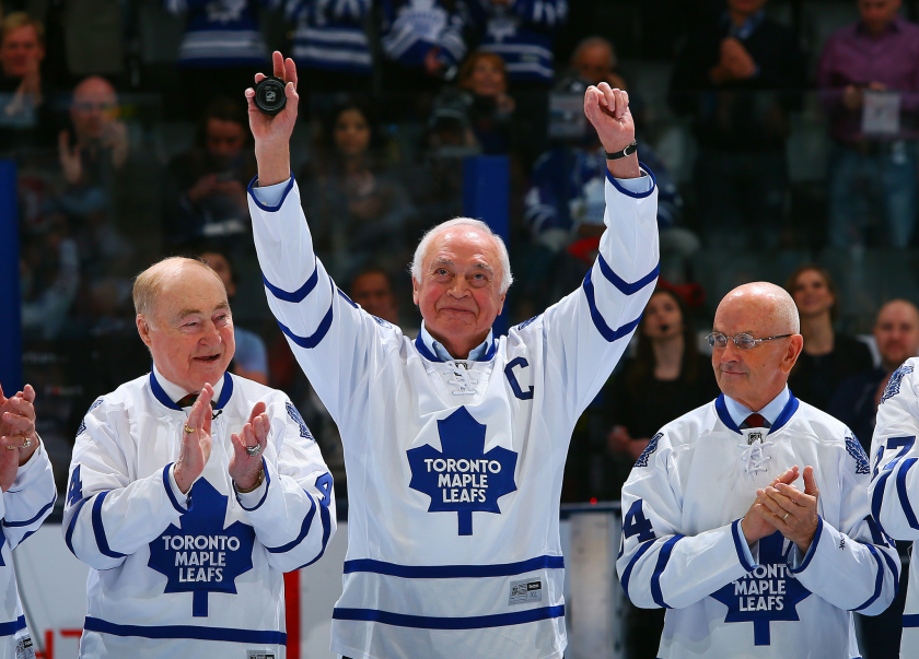 George Armstrong waves to the crowd at Air Canada Centre while flanked by other men in Toronto Maples Leafs shirts.