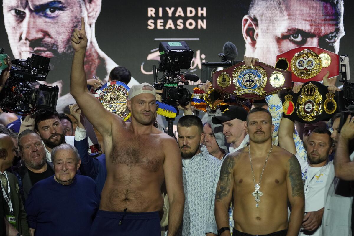 Heavyweight boxers Tyson Fury, left, and Oleksandr Usyk stand on the stage during a weigh-in 