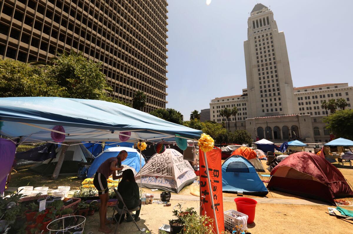 Randalee, left, braids the hair of a fellow camper at the Black Unity L.A. encampment across the street from City Hall.