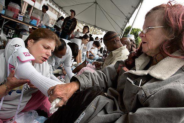 Volunteer Terri Sanchez, left, fits Linda Martin with new shoes at the annual Good Friday event hosted by the Los Angeles Mission. The mission, along with politicians and celebrities, served meals, provided children with Easter baskets, distributed new shoes and washed the feet of the homeless.