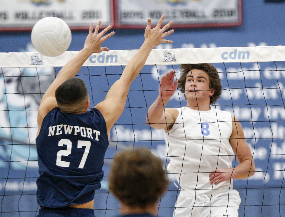 Corona del Mar's Reid McMullen (8) kills a ball past the block of Newport Harbor's Korbin Francisco (27) on Tuesday.