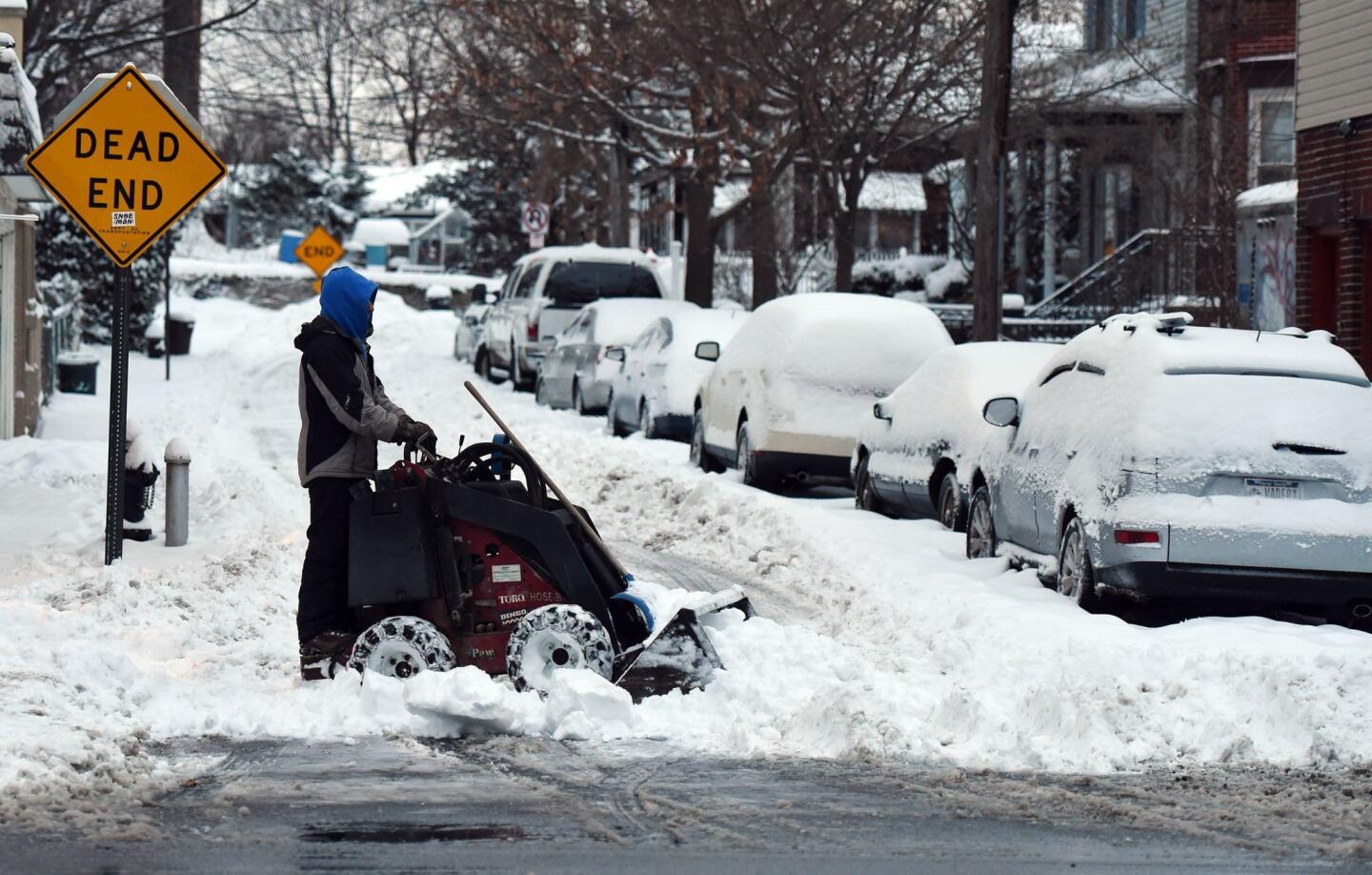 A man plows the sidewalk and street in the Bronx on Jan. 27, 2015.