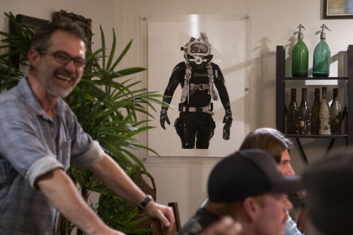 A picture of co-owner Emanuele Azzaretto, left, in his deep diving suit hangs in the tasting room at Ocean Fathoms wine.