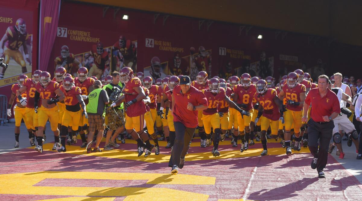 USC Coach Steve Sarkisian, center, leads the Trojans out of the tunnel at the Coliseum on Aug. 30 before a game against Fresno State.