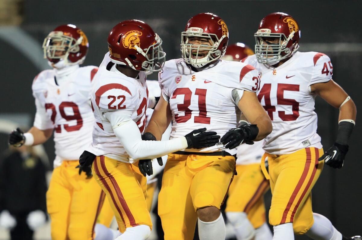 Soma Vainuku (31) enjoys the moment with USC teammates Leon McQuay III, left, and Charles Burks during the first quarter Saturday in Boulder.
