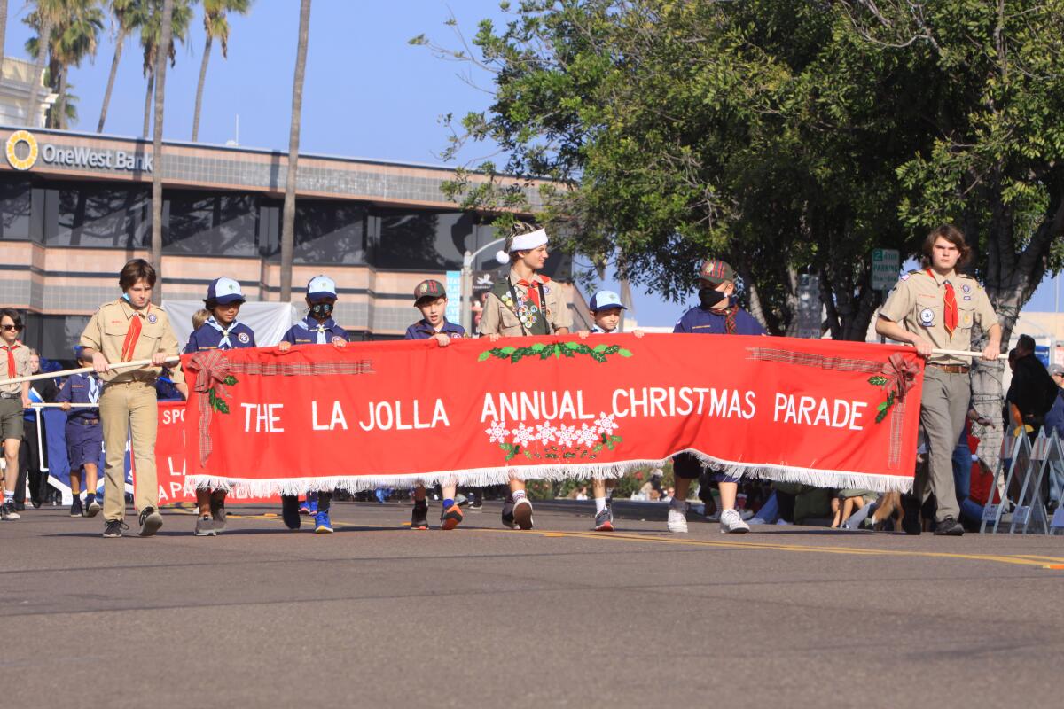 Boy Scouts from local troops carry the ceremonial banner to start the La Jolla Christmas Parade.