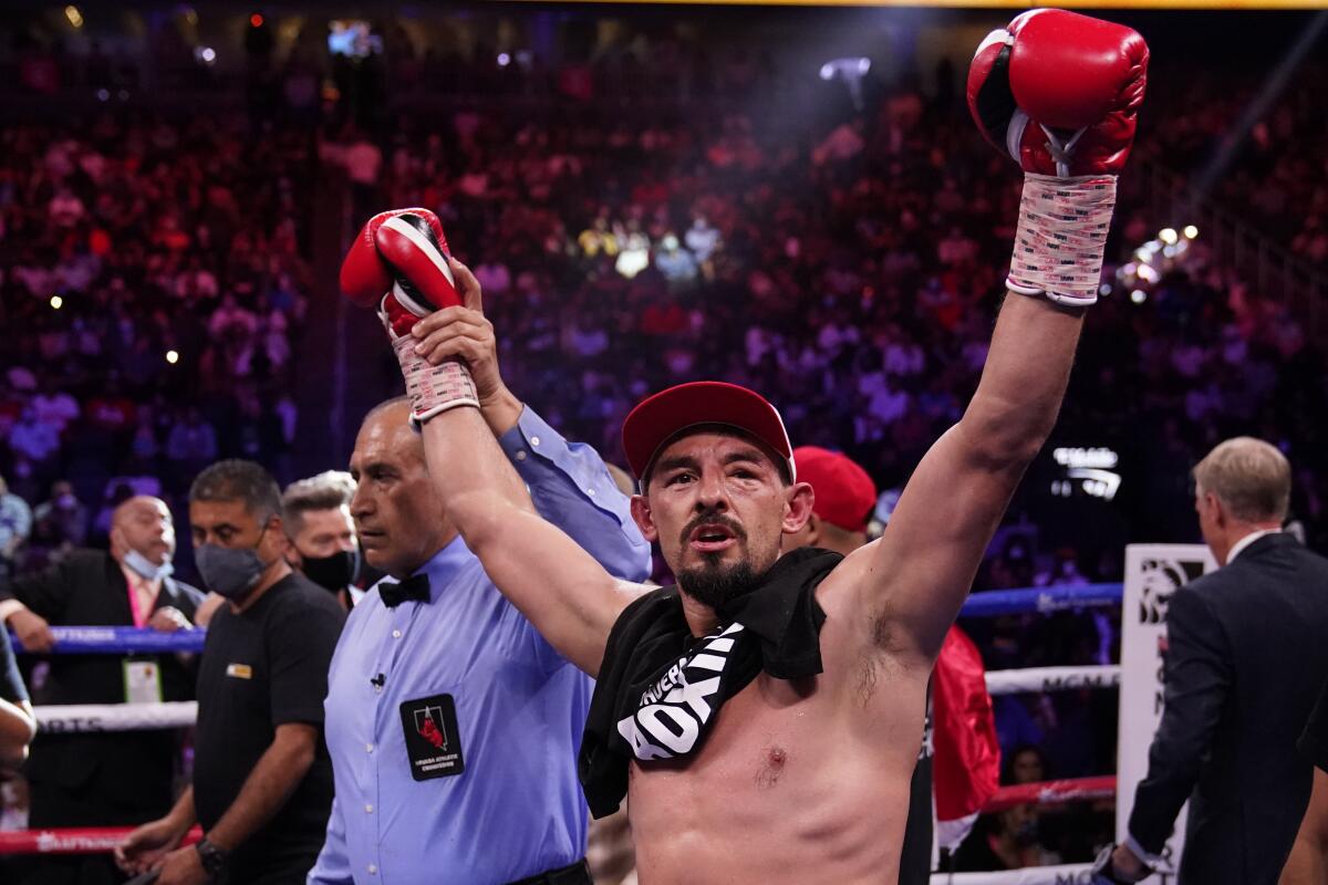 Referee Michael Ortega holds up Robert Guerrero's arm as he celebrates his win over Victor Ortiz